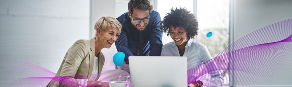 Two woman and a man gathered around a laptop