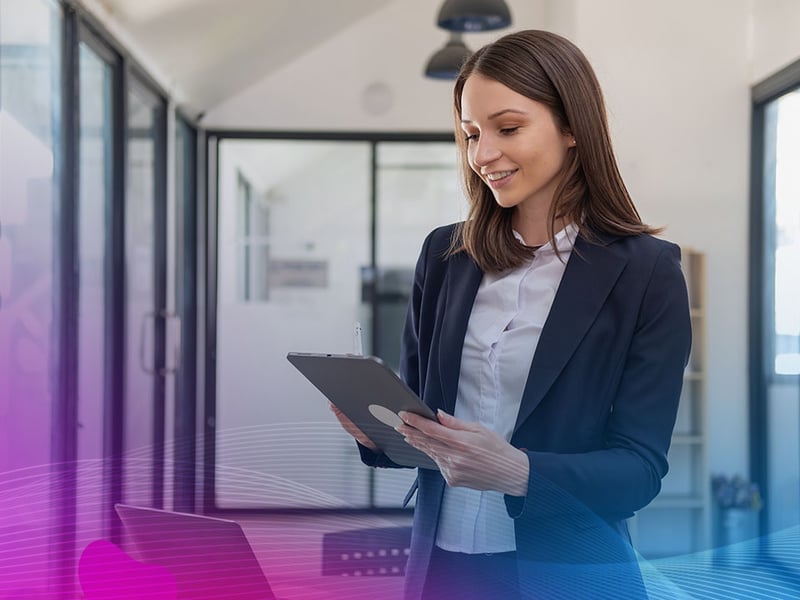 A stylish white business woman in a blacksuit standing inside the office in hands with a mobile phone